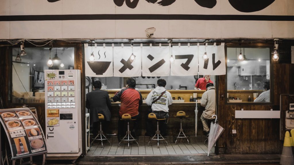 A small Japanese restaurant with a food ticket vending machine right by the entrance 